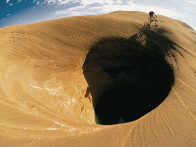 107432-FBA-Mountain-Biker-Cycles-Around-a-Spectacular-Crater-in-the-Desert-Poster